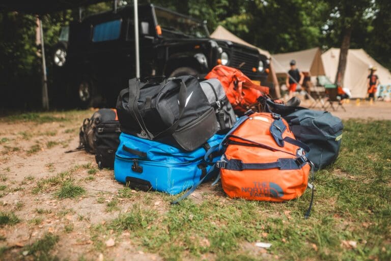 duffel bags and luggage at a campsite with a jeep